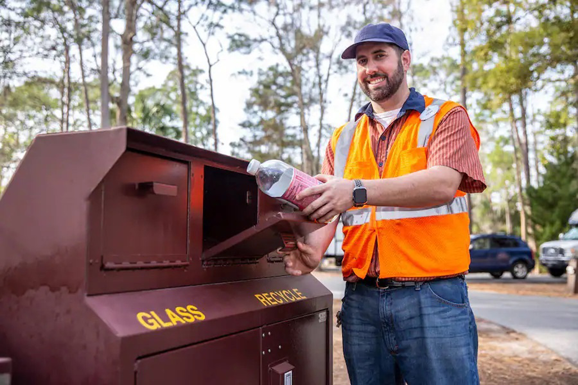 A Disney cast member recycling a plastic bottle into a receptacle.