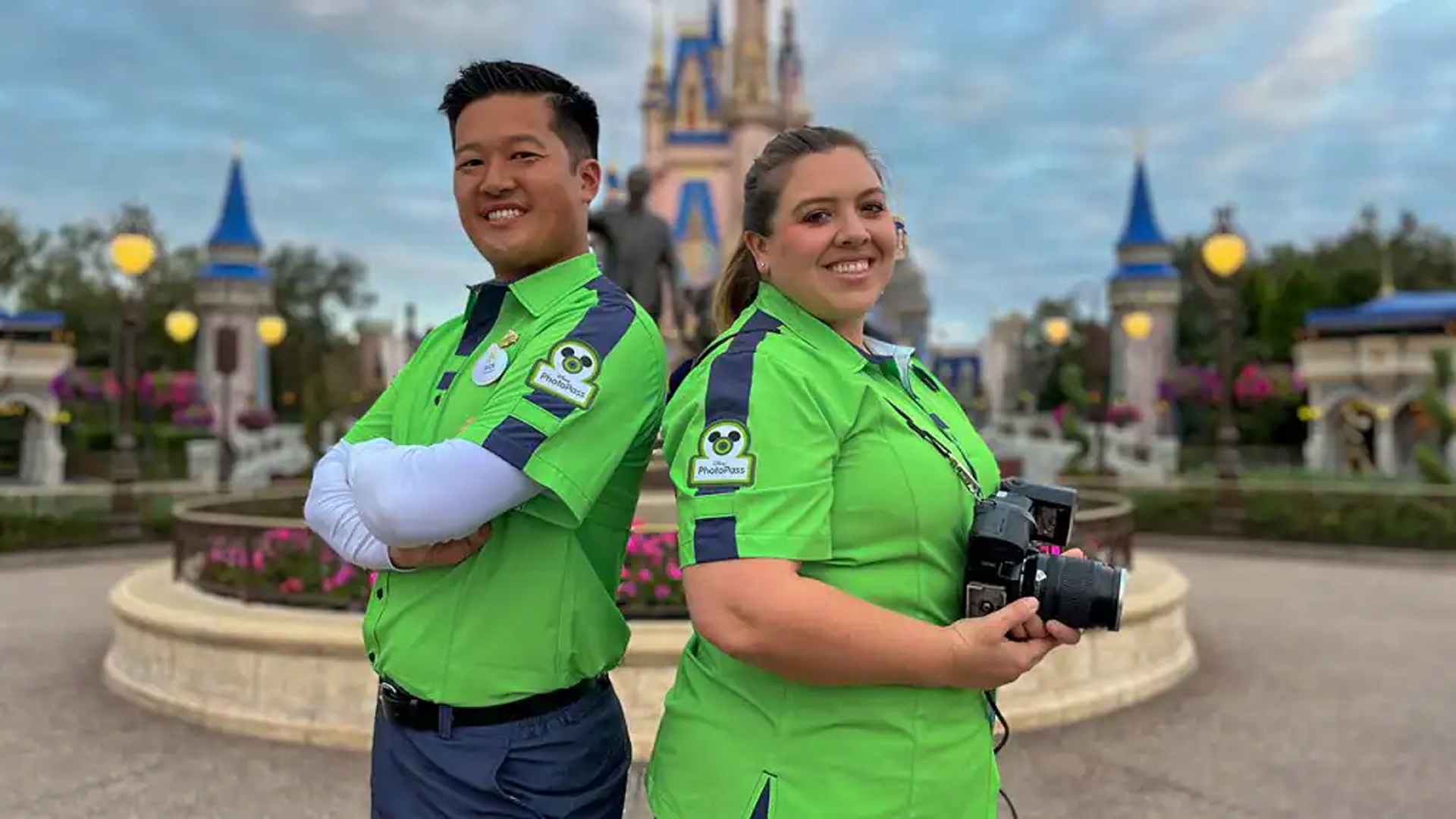 Two Disney PhotoPass cast members back-to-back in front of Cinderella’s castle.