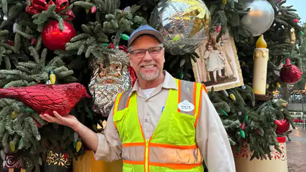 Martin standing in front of the huge tree showing off a cardinal ornament.